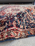 Vegetable dyed wool rug close view of deep red, navy blue, and ivory hand-spun yarns.