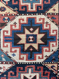 Close up of antique Caucasian wool rug with floppy handle and low pile construction.