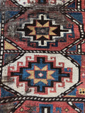 Shabby chic antique Kazak rug with tribal pattern and scattered wear.