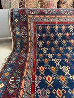 Corner view of small Caucasian rug handwoven by nomads with intricate tribal design.