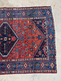 Hand knotted antique Persian wool rug with jewel toned dyes, geometric movement, and tribal character throughout.