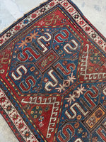 Close-up of red and ivory cloud bands on an ocean blue Kazak rug.
