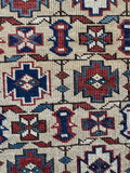 Close up of antique Caucasian rug with angular tribal motifs and vegetable dyed wool.