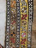 Close up of early 1900s tribal hallway runner with floral chain border in cheerful yellow tones.