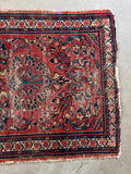 Antique wool mat detail showcasing fine hand-knotted stitching and rich red and navy botanical motifs.