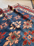 Caucasus mountain handwoven antique rug with traditional blue and red coloring.