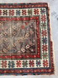 Antique tribal rug detail showing a crisp ivory border filled with colorful geometric motifs.