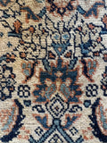 Authentic Persian water garden rug close up detail of dark blue floral lattice and tan field.