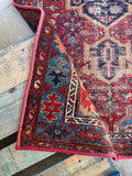 Vintage Persian Heriz area rug. Antique geometric wool carpet featuring a striking medallion, tribal artwork, and beautifully aged vegetable dyes.