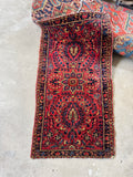 Red and navy floral Persian rug shown in full from overhead.