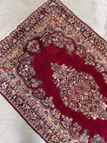 1930s vintage Persian Sarouk wool rug featuring a detailed center medallion and vibrant vegetable-dyed berry red background.