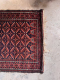 Small 3x4 antique tribal rug one end view photo highlighting geometric symmetry and rich tribal motifs.