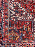 Authentic Persian Heriz rug with geometric motifs, deep navy border, and brick red field.