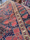 Antique Persian tribal carpet with abrash blues and warm terracotta medallions.