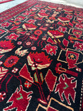 3x6 Small vintage Persian tribal rug 3x6 corner detail, black ground with red animal angle shot of saturated dyes