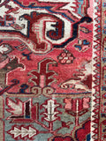 Close up of antique Persian rug with vibrant vegetable dyes in crimson, navy, aqua, and camel.