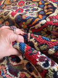 Persian vintage rug detail showing luxurious wool texture and supple weave under hand.