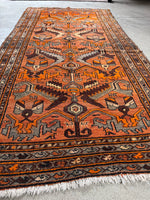 Vibrant orange ground with playful tribal motifs.