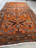 Vibrant orange ground with playful tribal motifs.