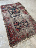 Distressed 19th century Persian rug with navy blue ground and faded graphic elements.