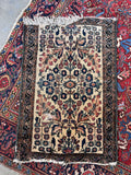 Vintage 1920s ivory Persian entry rug overhead view highlighting the compact size, dark navy borders, and traditional botanical layout.
