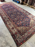 Handwoven Persian rug showing scattered wear and aged character.