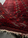 Vintage Afghani rug styled on a concrete floor with soft drape.