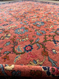 Hand knotted wool area rug in rare salmon coral with low wear and authentic antique patina.