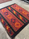 Flatwoven Turkish rug with stacked angular medallions, zigzag motifs, and a grounding near-black border.