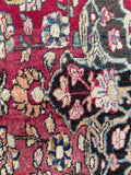 Persian rug with a berry red center, intricate floral motifs, and a rich navy main border.
