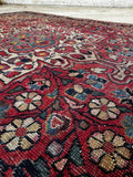 Close-up of saturated madder red field and multi-colored floral artwork.