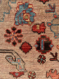 Close-up of vintage Persian rug with geometric blossoms and rhubarb red tones.