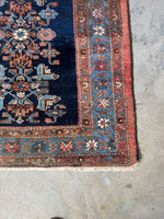 Corner view of antique Malayer rug displaying warm tones and botanical-inspired central column.