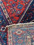 1920s Persian Malayer village rug with rich abrash, floral elements, and strong tribal geometric design.