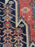 Geometric Mazlaghan rug pattern close-up highlighting floral motifs against a rich dark navy blue ground.
