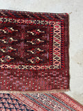 Antique Persian Yomut bag face laid on floor, illustrating its compact 2'5 x 4'5 size and rich color depth.