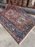 Vintage Persian rug featuring three poled medallions on a warm red field with a navy border.