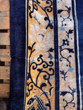 Blue and gold antique Chinese rug detail shot of the broad golden border with scrolling vines and butterflies.