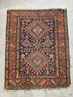 Persian Heriz scatter rug from the 1920s, showcasing a scorpion center medallion, symbolic ram’s horns, and geometric border design.