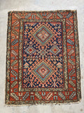 Persian Heriz scatter rug from the 1920s, showcasing a scorpion center medallion, symbolic ram’s horns, and geometric border design.