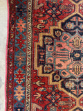 Antique Persian tribal rug. Vintage Heriz carpet with colorful geometric artwork, scattered wear, reinforced bound edges, and heirloom craftsmanship.