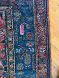 Low pile antique Persian rug with navy border and floral medallion motifs throughout.