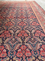 Vintage Persian rug featuring repeating motifs on a dark ground.