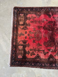 Ombre ground color detail on a vintage Persian rug in rich red shades.