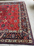 One end of antique Tabriz rug with glowing red field and subtle orange undertone.