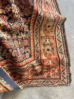 Persian rug from the 1920s with bold border design and soft wool texture.