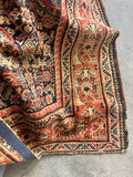 Persian rug from the 1920s with bold border design and soft wool texture.