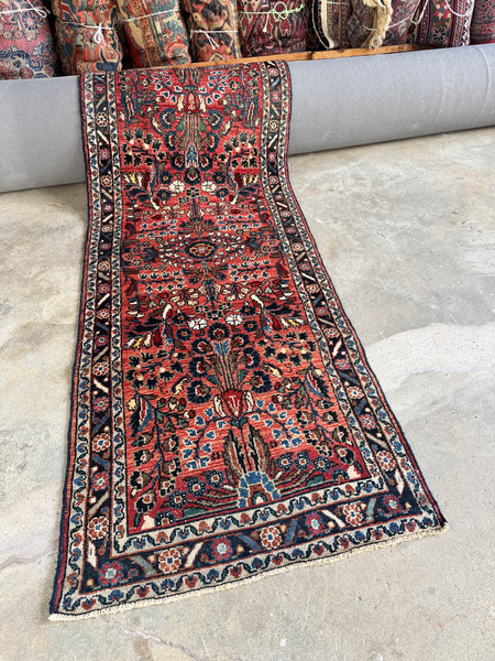 Narrow vintage Persian runner with peacock-like floral motifs and warm coral abrashed ground.