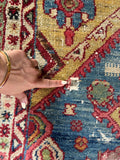 Distressed yellow Persian rug detail showing authentic 19th-century weave, natural dye patina, and one small hole.