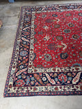 One end of large antique Tabriz rug with curvilinear floral motifs and navy border detail.